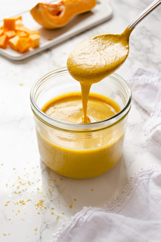 A jar of creamy butternut squash nut-free vegan cheese sauce