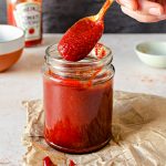 Stiring a jar of homemade bbq sauce with a spoon